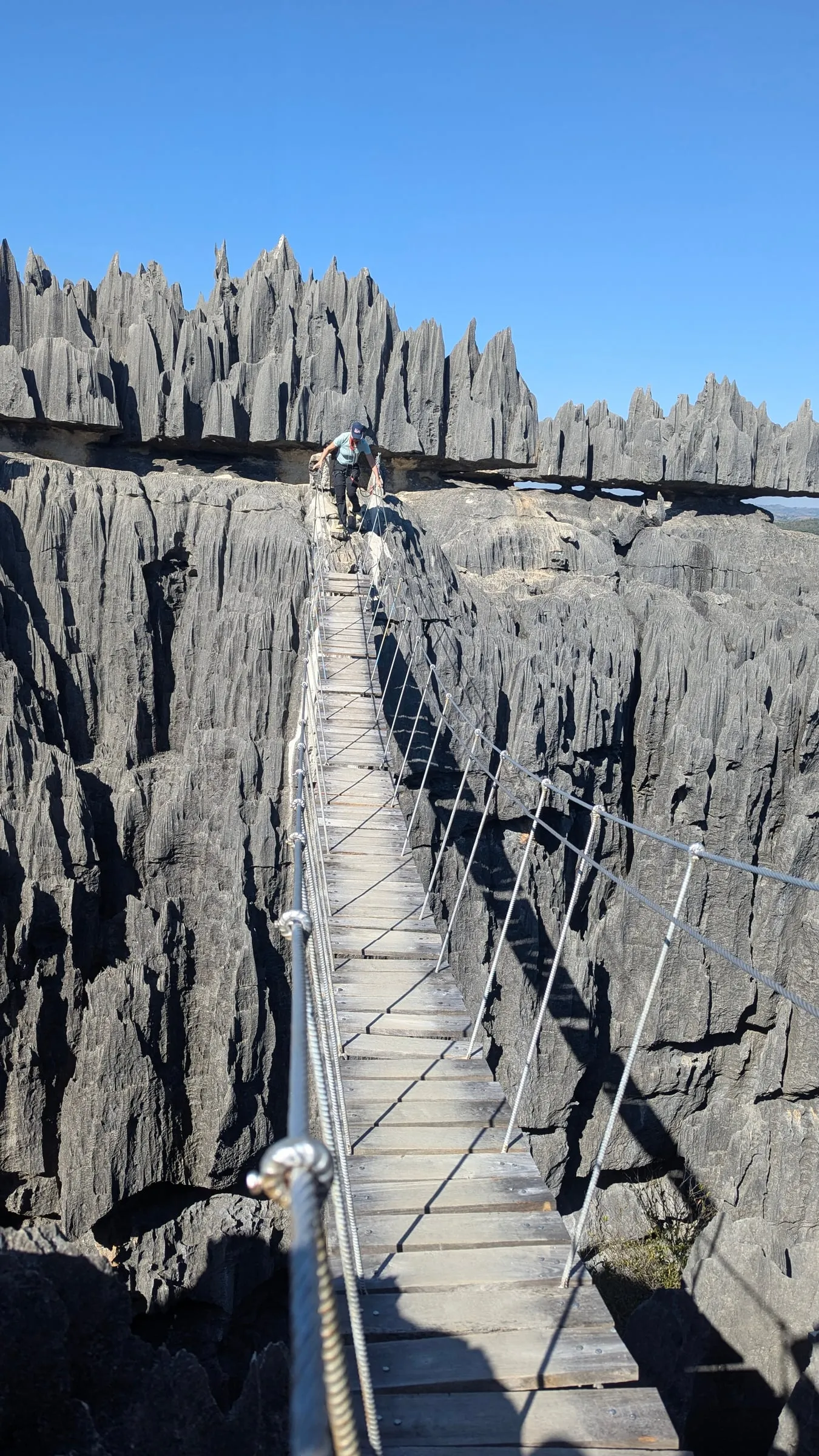 A traveller crossing a suspension bridge above the Tsingy de Bemaraha