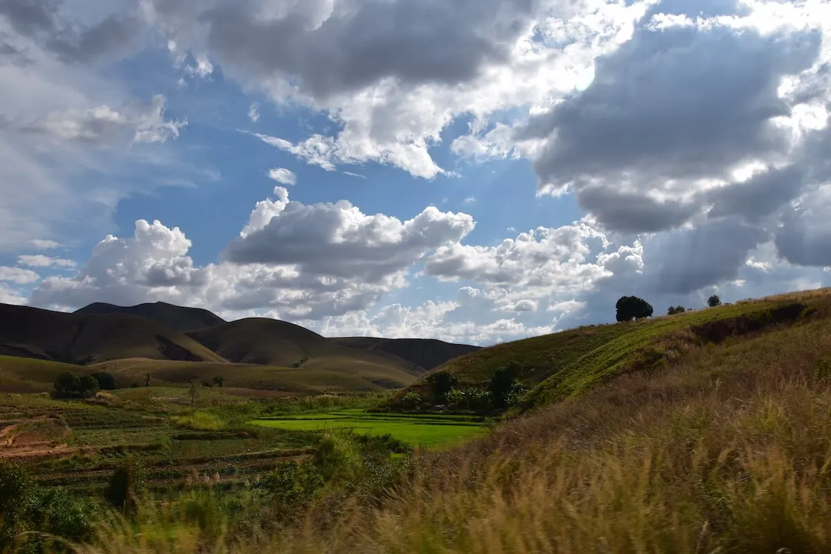 Collines verdoyantes et rizières des Hautes Terres sous un ciel nuageux